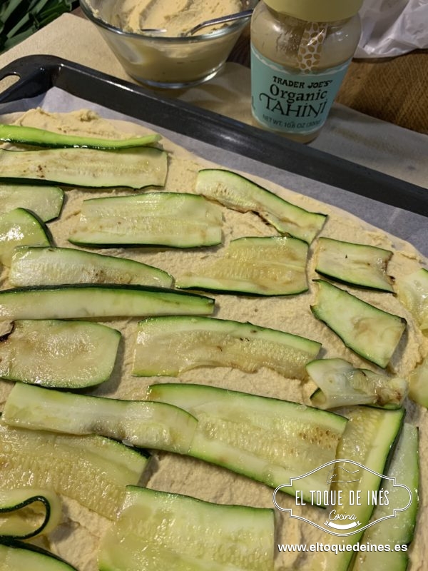 Extendemos la masa con las manos o con un rodillo sobre papel de horno en la bandeja elegida.